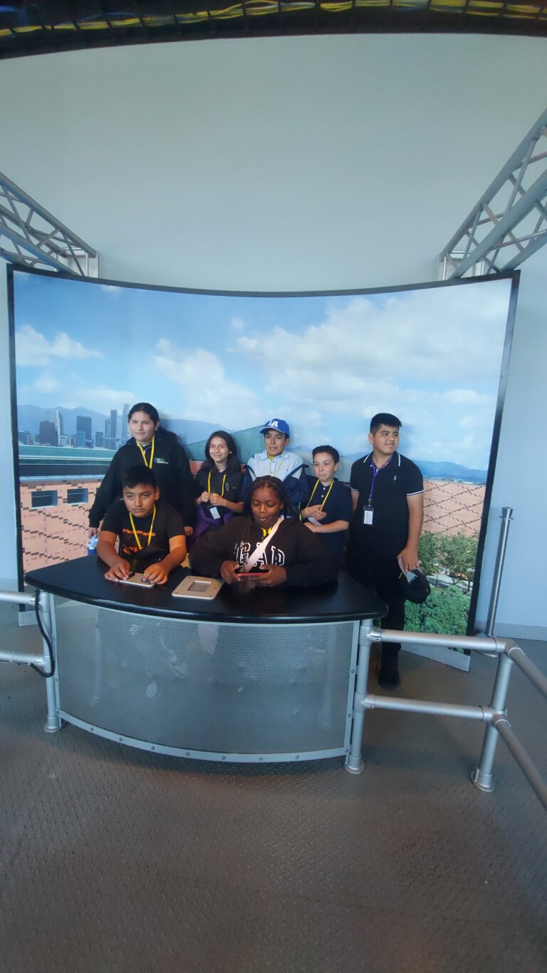 A group of students posing together at a museum exhibit on a field trip