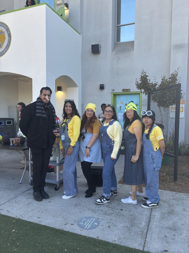 A staff member with students in matching yellow and denim outfits for spirit day